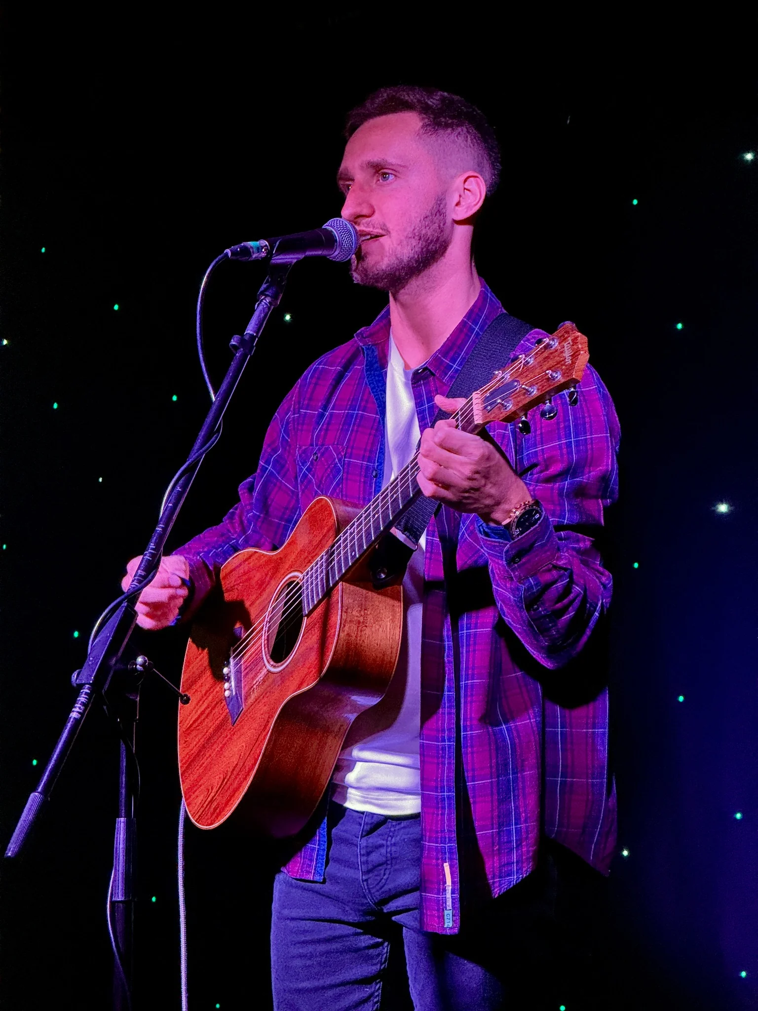Agustin Kafka singing and playing acoustic guitar during a live performance